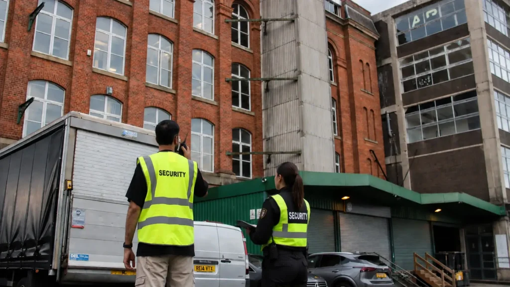 Two USSG security officers in high-visibility vests outside a red-brick building